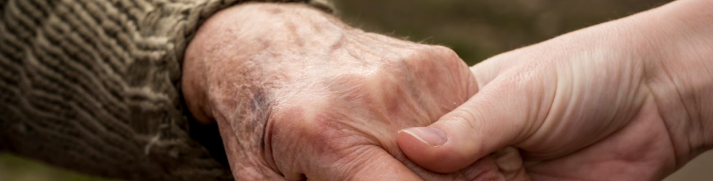 A volunteer holding the hand of an elderly man.